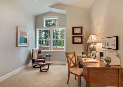 A well-organized home office with a wooden desk, chair, and a window offering scenic views of trees and nature.