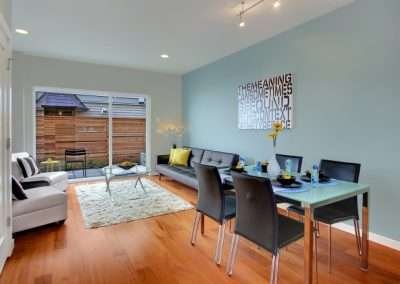 A contemporary living and dining space with modern furniture, a glass dining table, and a large window.