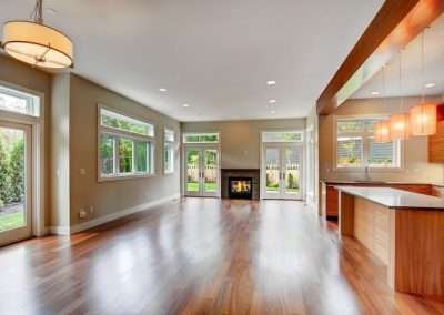 A spacious living area with hardwood floors, a built-in fireplace, and large windows overlooking the garden.