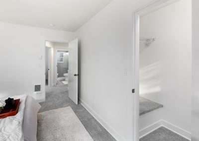 A bright walk-in closet with wire shelving and small windows, featuring ample storage space.