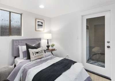 A bedroom with a bed, decorative pillows, and a door leading to an outdoor area.