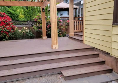 Custom composite deck with a wooden pergola and wide stairs, enhancing the outdoor space of a Seattle home. Built by expert deck and patio contractors in Seattle for functionality and aesthetic appeal.