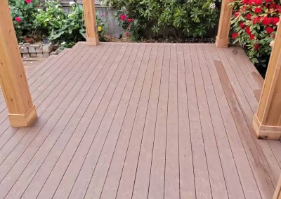 Beautiful wooden pergola with a transparent roof, built over a composite deck in a landscaped Seattle backyard. Designed by expert patio and deck contractors in Seattle for a stylish and functional outdoor space.
