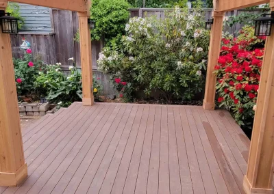 Beautiful wooden pergola with a transparent roof, built over a composite deck in a landscaped Seattle backyard. Designed by expert patio and deck contractors in Seattle for a stylish and functional outdoor space.