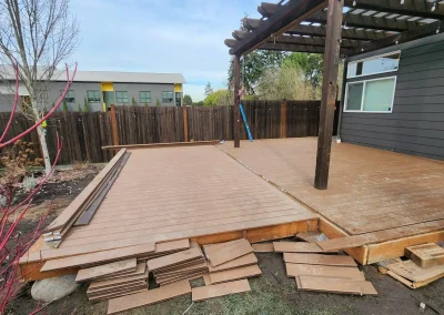 Ongoing deck renovation with a new composite deck extension being installed alongside an existing pergola-covered patio in a Seattle backyard. Built by expert deck contractors in Seattle for durability and modern outdoor living.