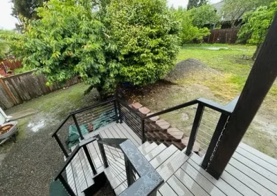 Modern composite deck with black metal cable railing and custom stairs leading to a landscaped backyard in Seattle. Built by expert deck contractors in Seattle for safety and style.
