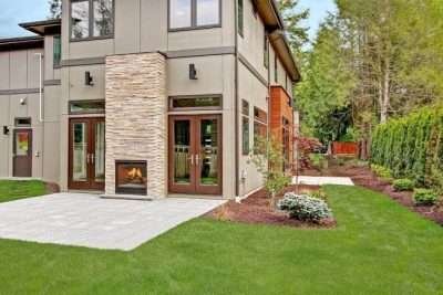A modern open-plan living area with a cozy sofa, fireplace, dining table, and kitchen in the background.